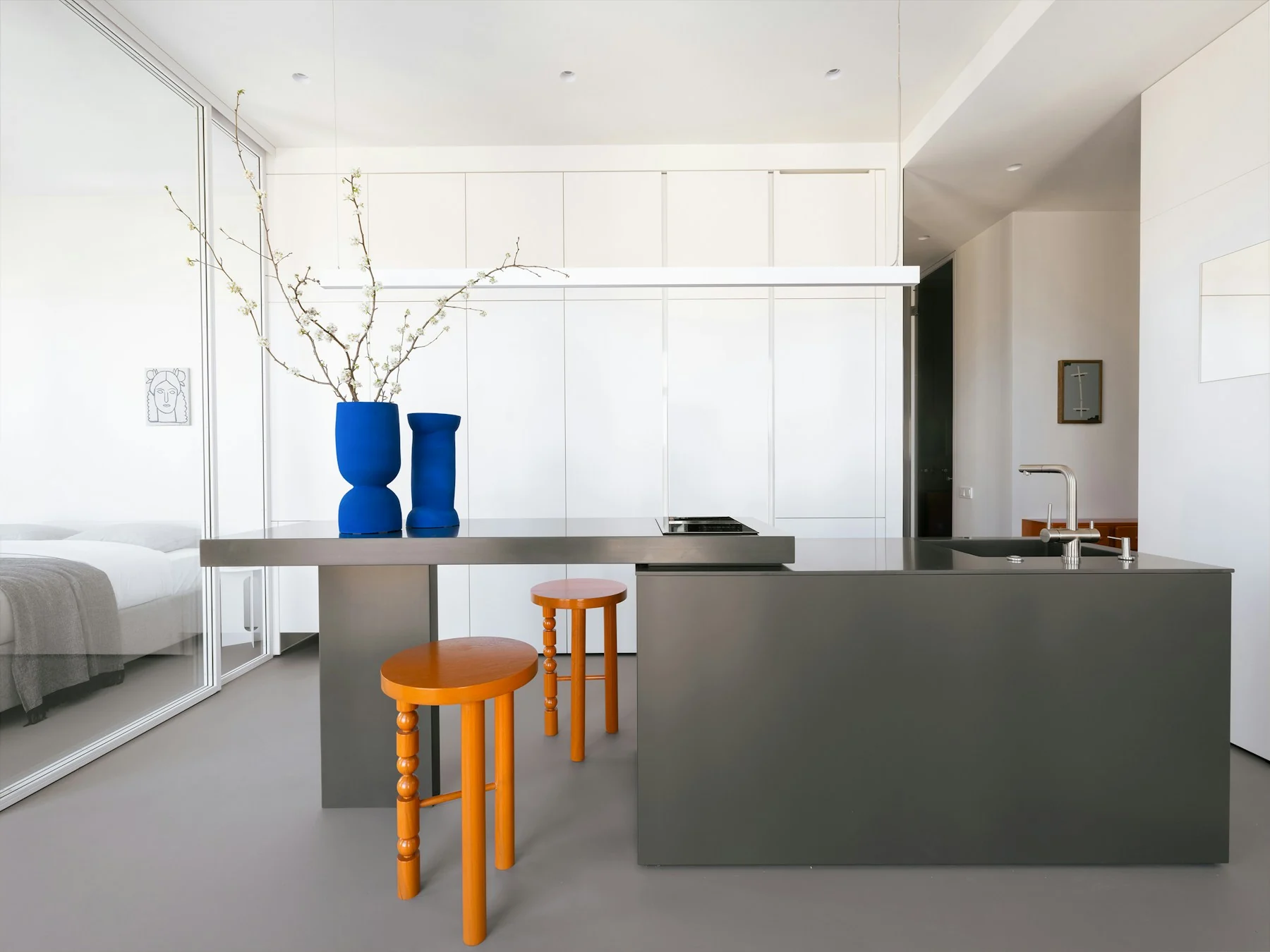 A considered contemporary kitchen with sculptural stools, neutral cabinetry and blue vessels